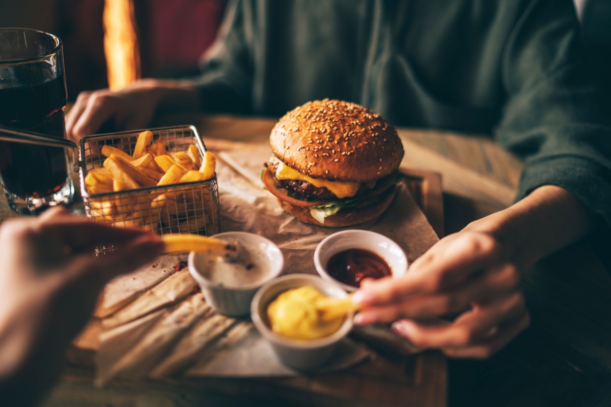 Burger and chips with friends. Photography by ESstock. Image via Shutterstock