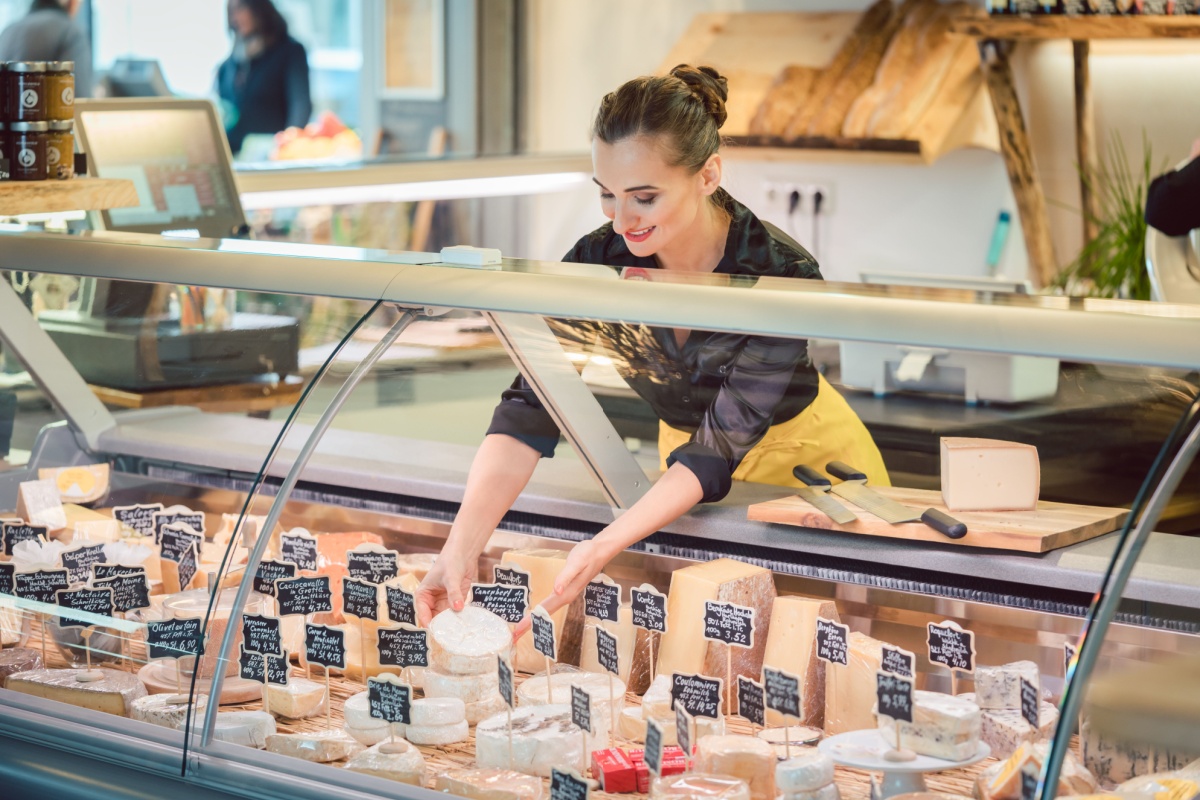 Woman working at cheese shop. Photography by Kzenon. Image via Shutterstock