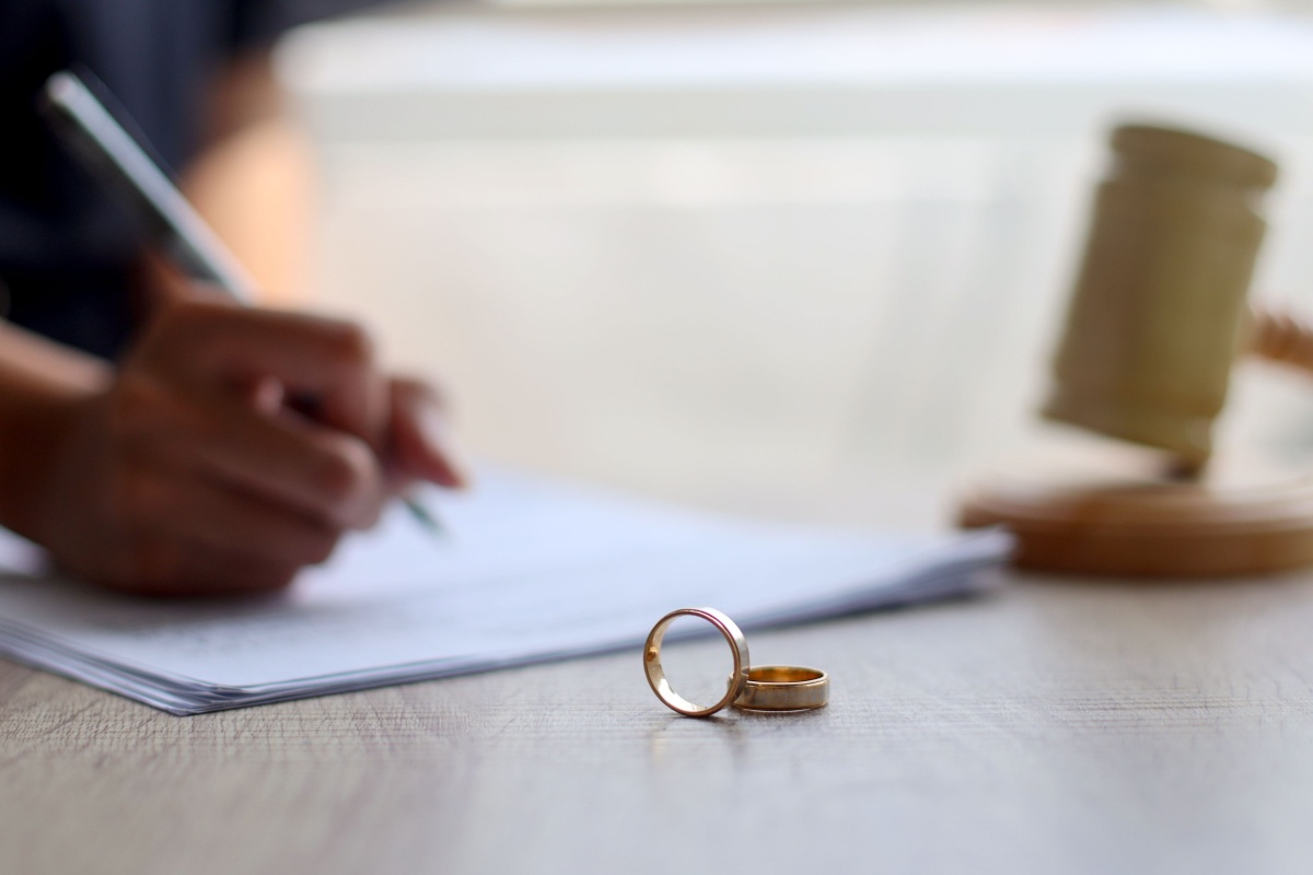 Wedding rings on a table, with document in background. Photography by Queenmoonlite Studio. Image via Shutterstock