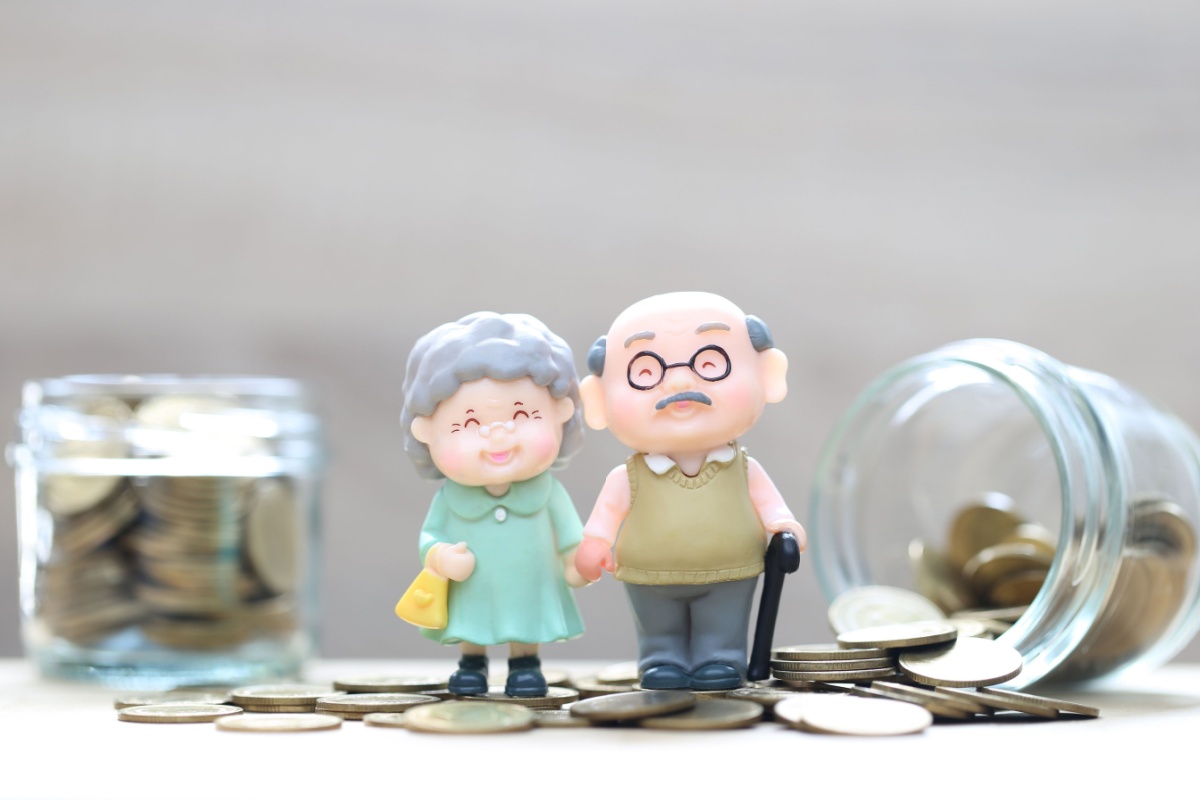 Old couple dolls around coins. Photography by Monthira via Shutterstock