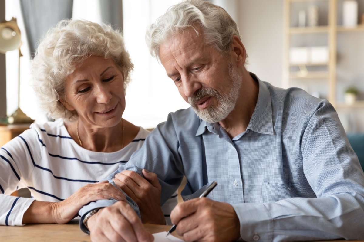 Older couple signing document. Photography by fizkes via Shutterstock